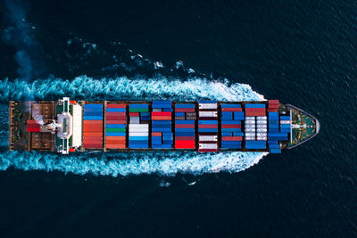 Aerial top view full speed container ship in the deep blue sea for cargo logistics import and export 