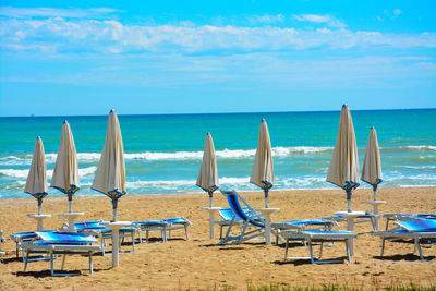 Chairs on beach by sea against sky