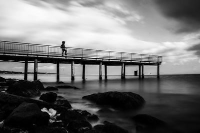 People standing on bridge over sea against sky