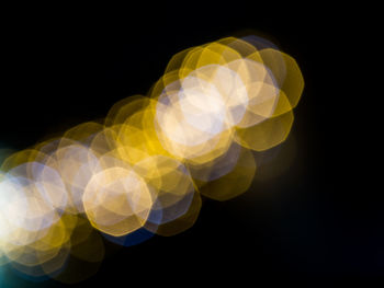 Defocused image of illuminated lights against black background