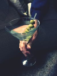 High angle view of person holding martini with olives at home