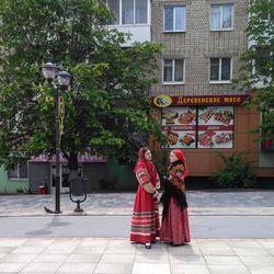 Woman with red umbrella against trees in city