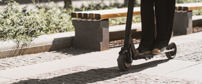 Low section of woman on push scooter at road