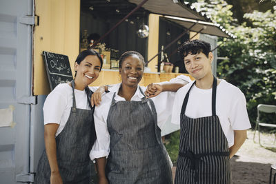 Smiling male and female colleagues standing by food truck in park