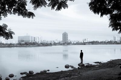 Rear view of man standing by cityscape against sky