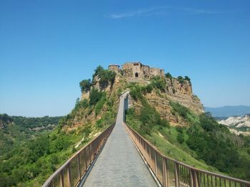 Low angle view of walkway leading towards castle against blue sky