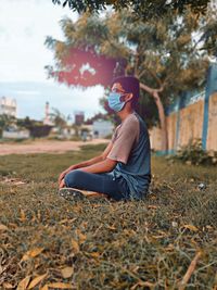 Side view of young woman sitting on field