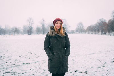 Portrait of woman in warm clothing standing on snow against sky