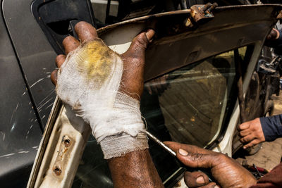 Cropped hand of injured mechanic repairing car door