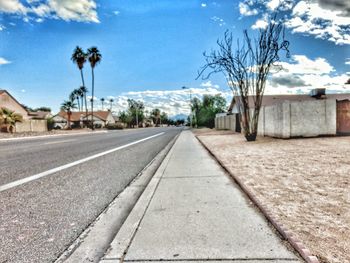 Road by trees against blue sky