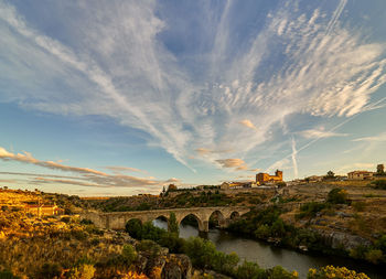 Arch bridge over river against sky during sunset