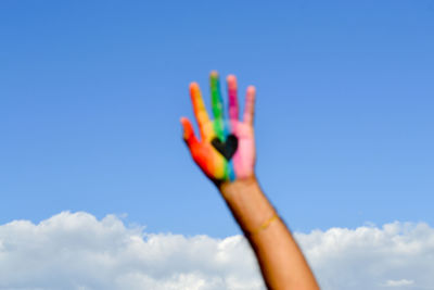 Low angle view of woman hand against blue sky