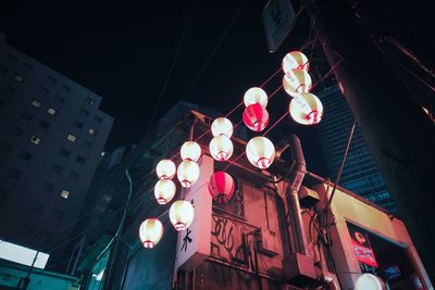 Low angle view of illuminated lanterns hanging by building at night