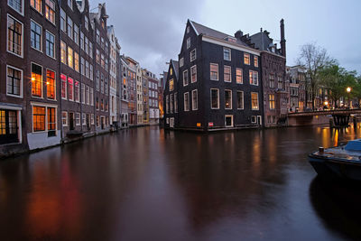 Canal amidst buildings in city at dusk