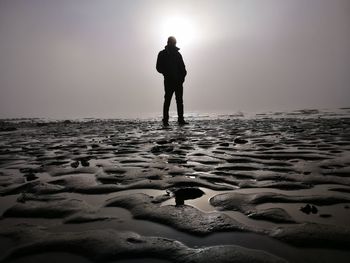 Silhouette man standing on beach against clear sky
