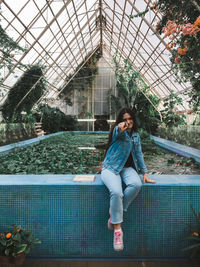 Full length of woman sitting against plants