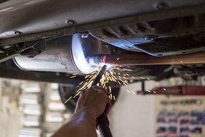 Cropped hand of mechanic repairing car in workshop