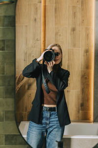 Woman photographing through camera seen in bathroom mirror