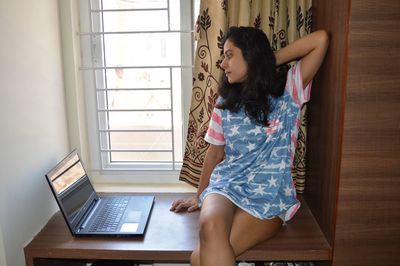 Young woman with laptop on table sitting at home