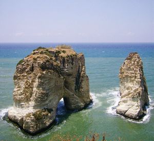 Rock formation in sea against clear sky