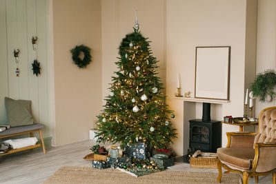 Scandinavian beige christmas interior with decorated christmas tree. fireplace with armchair, wreath