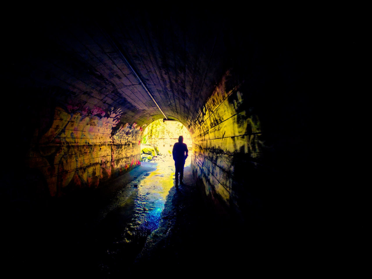 SILHOUETTE OF PERSON IN ILLUMINATED TUNNEL