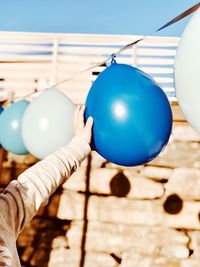 Midsection of person touching balloon hanging from string