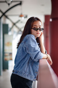 Beautiful young woman wearing sunglasses standing by railing