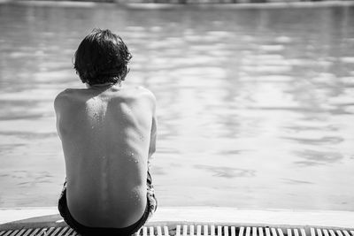 Rear view of shirtless man standing in swimming pool