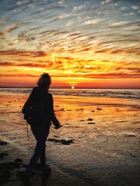 Woman looking at sea against sky during sunset