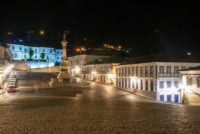 Illuminated street amidst buildings in city at night