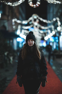 Portrait of woman standing in illuminated park during winter