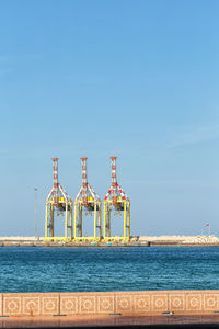 Tower by sea against clear blue sky