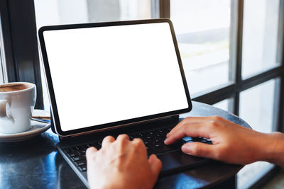 Cropped hands using laptop at table