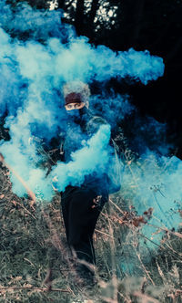 Man standing in forest spreading smoke 