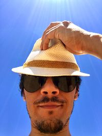 Portrait of man wearing sunglasses and hat against clear blue sky