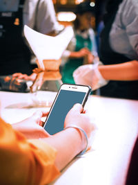 Midsection of man using mobile phone on table