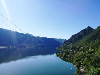 Scenic view of lake and mountains against clear blue sky