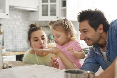 Father by mother and daughter preparing food in kitchen