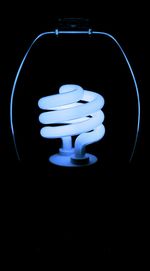 Low angle view of illuminated lighting equipment against black background