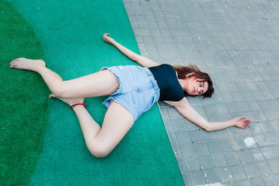 Young depressed woman lying on the ground in a backyard