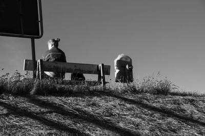 Men sitting on field against clear sky