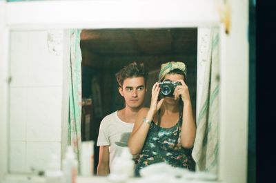 Reflection of man photographing on mirror