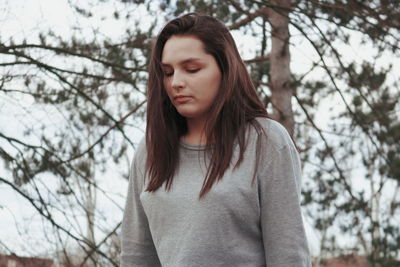 Beautiful young woman standing against trees