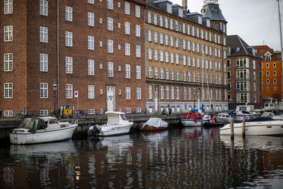 Sailboats moored on canal by buildings in city