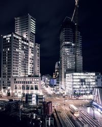 Modern buildings in city against sky at night