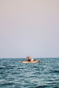 Boat sailing in sea against clear sky