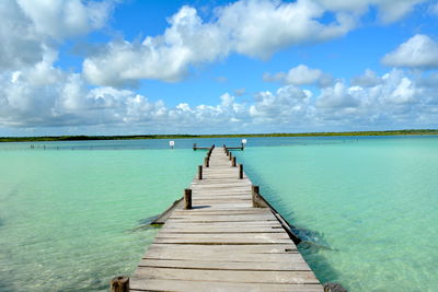 Wooden pier over sea against sky