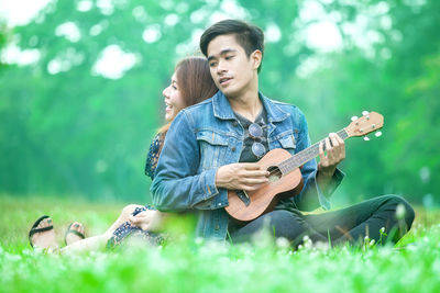 Young man playing guitar on grass