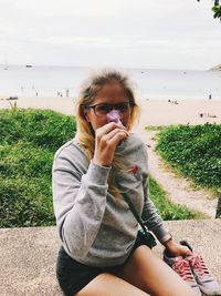 Portrait of woman smelling flower against sea